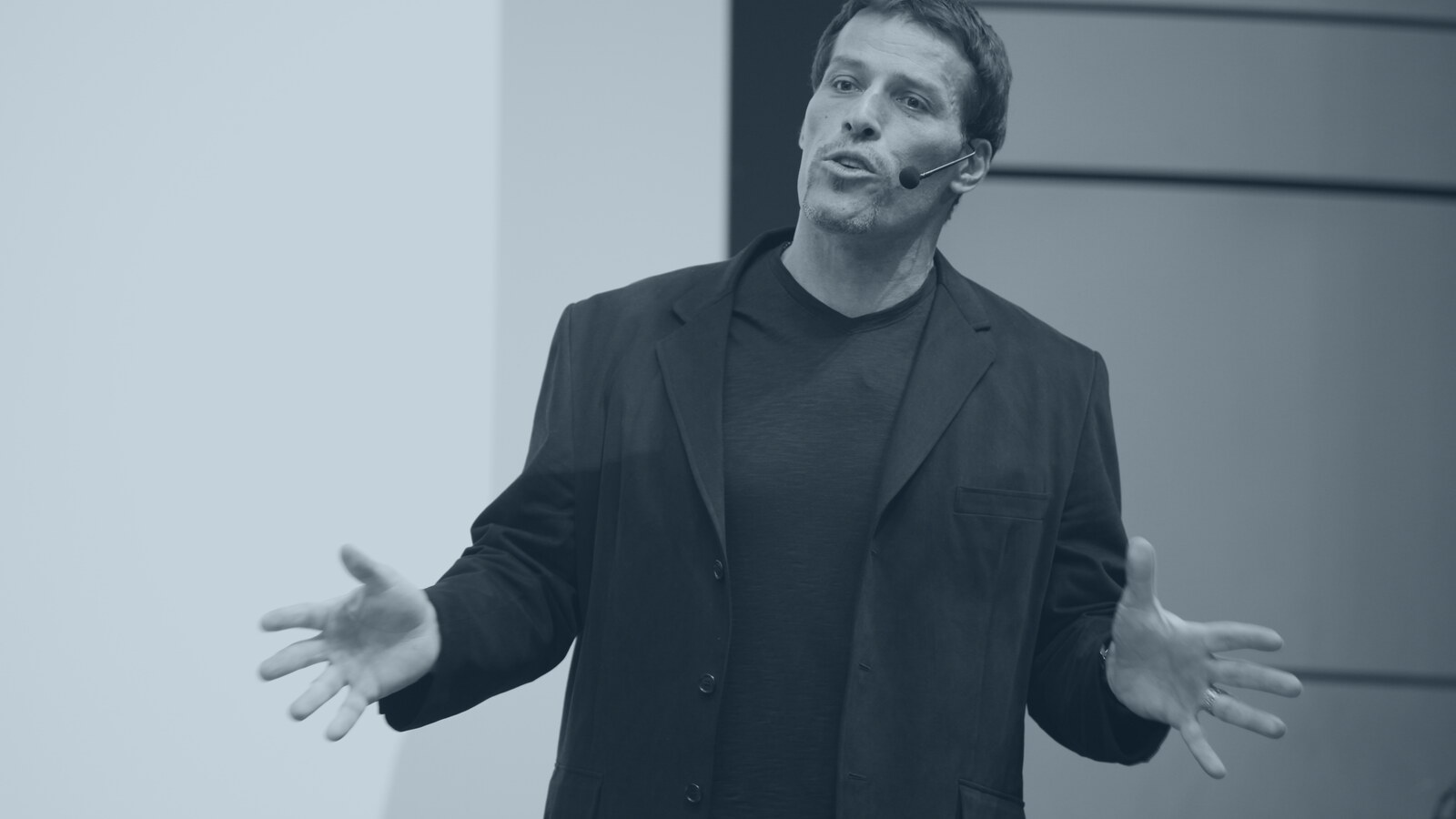Tony Robbins auf der Bühne, gestikulierend, im Steel-Monochrom-Look